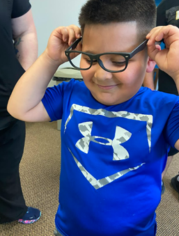 young boy putting on glasses